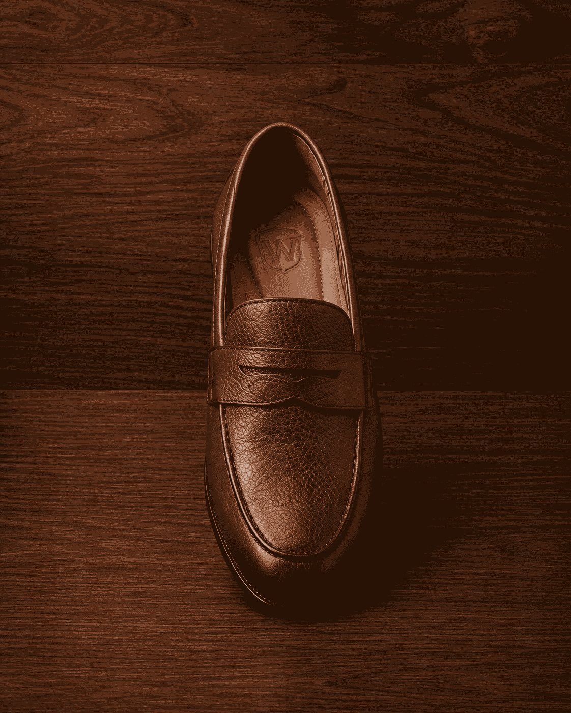 Top-down view of brown pebbled leather penny loafer showing moc-toe stitching and branded leather footbed